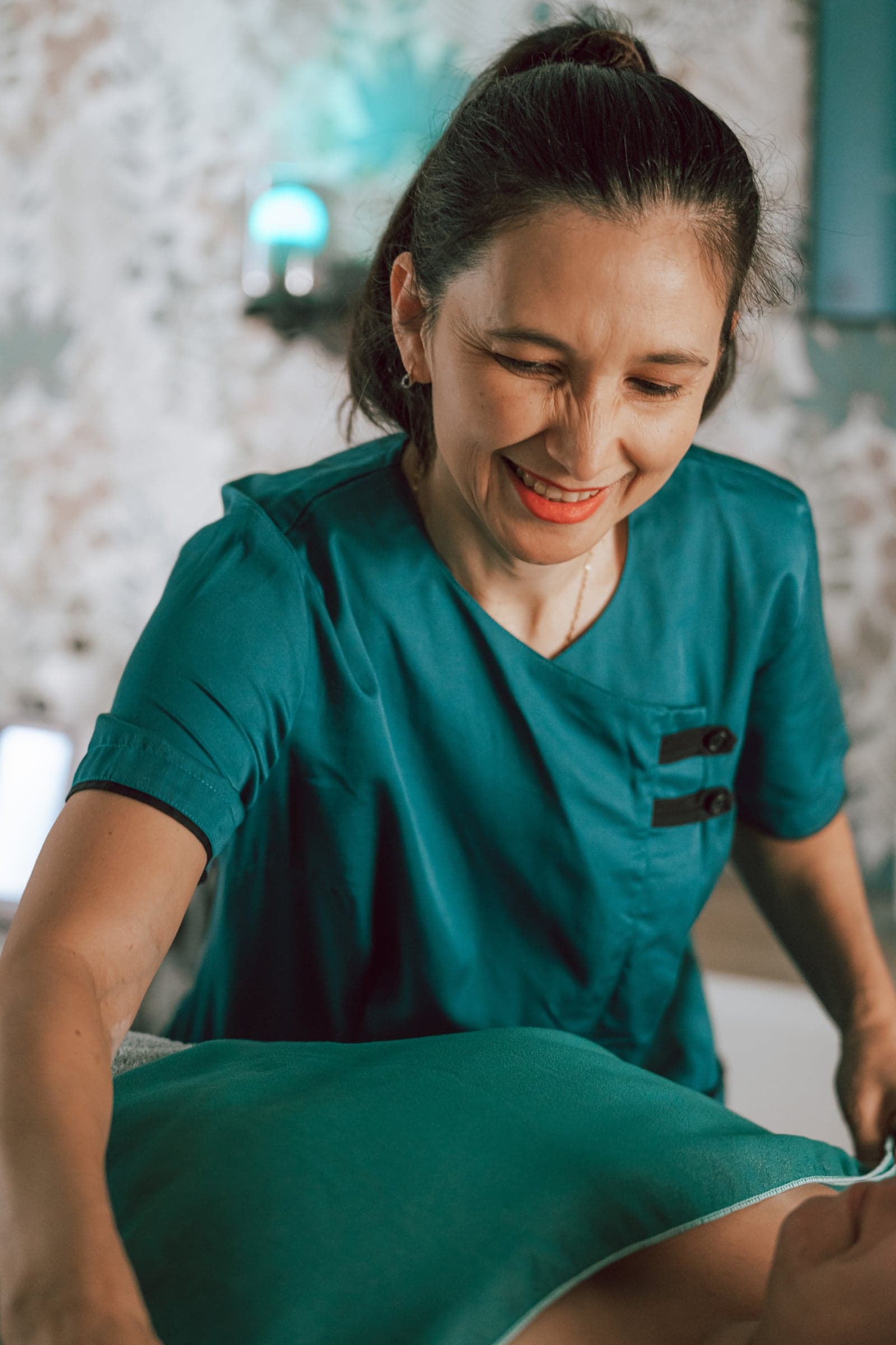 Portrait de Delmi, praticienne diplômée d'État, souriante en pleine séance dans son cabinet de Vertou