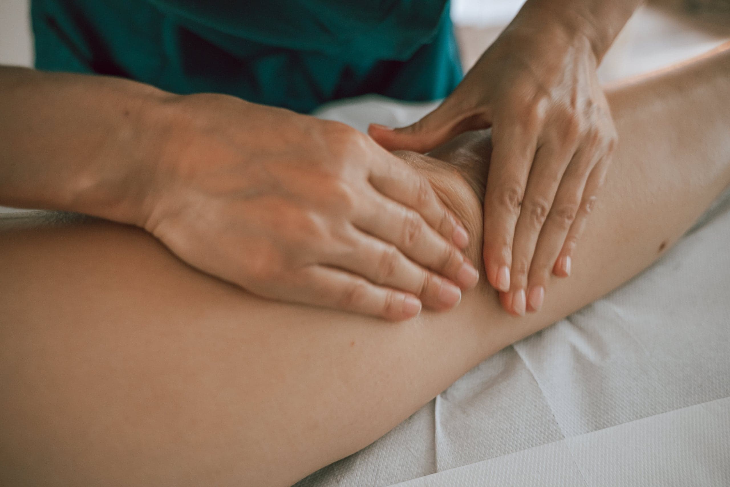 Mains posées à plat sur la cuisse d'une cliente pendant un massage relaxant, dans le cabinet de Vertou